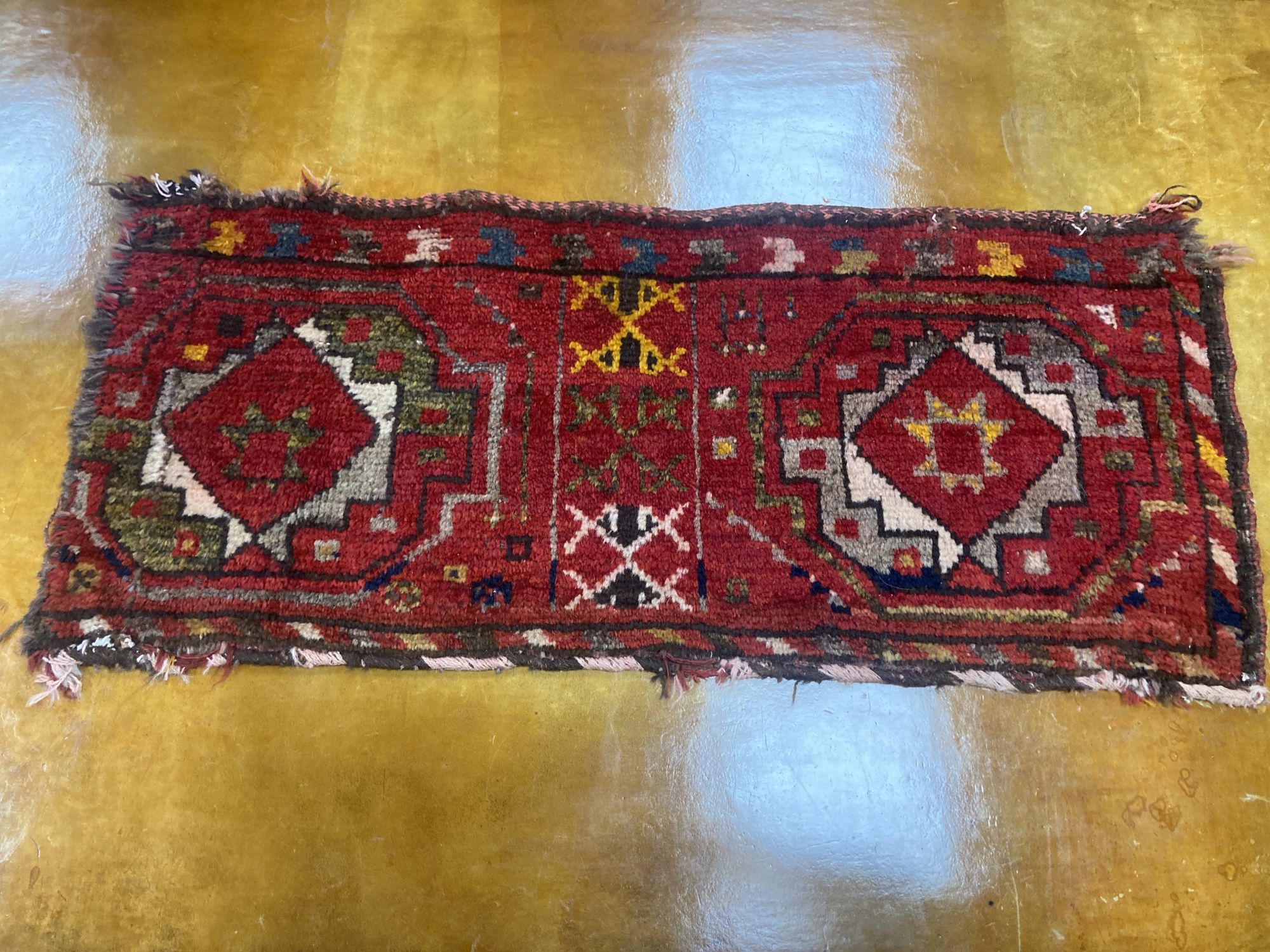 Six Caucasian design mats and a saddlebag, largest 140 x 60cm